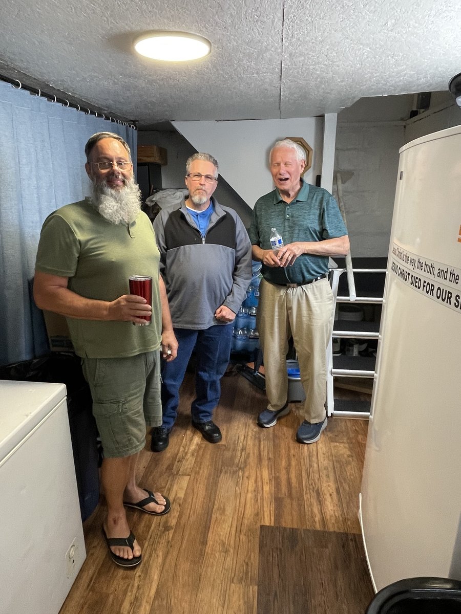 Church members talking together near a chest freezer during a fellowship gathering