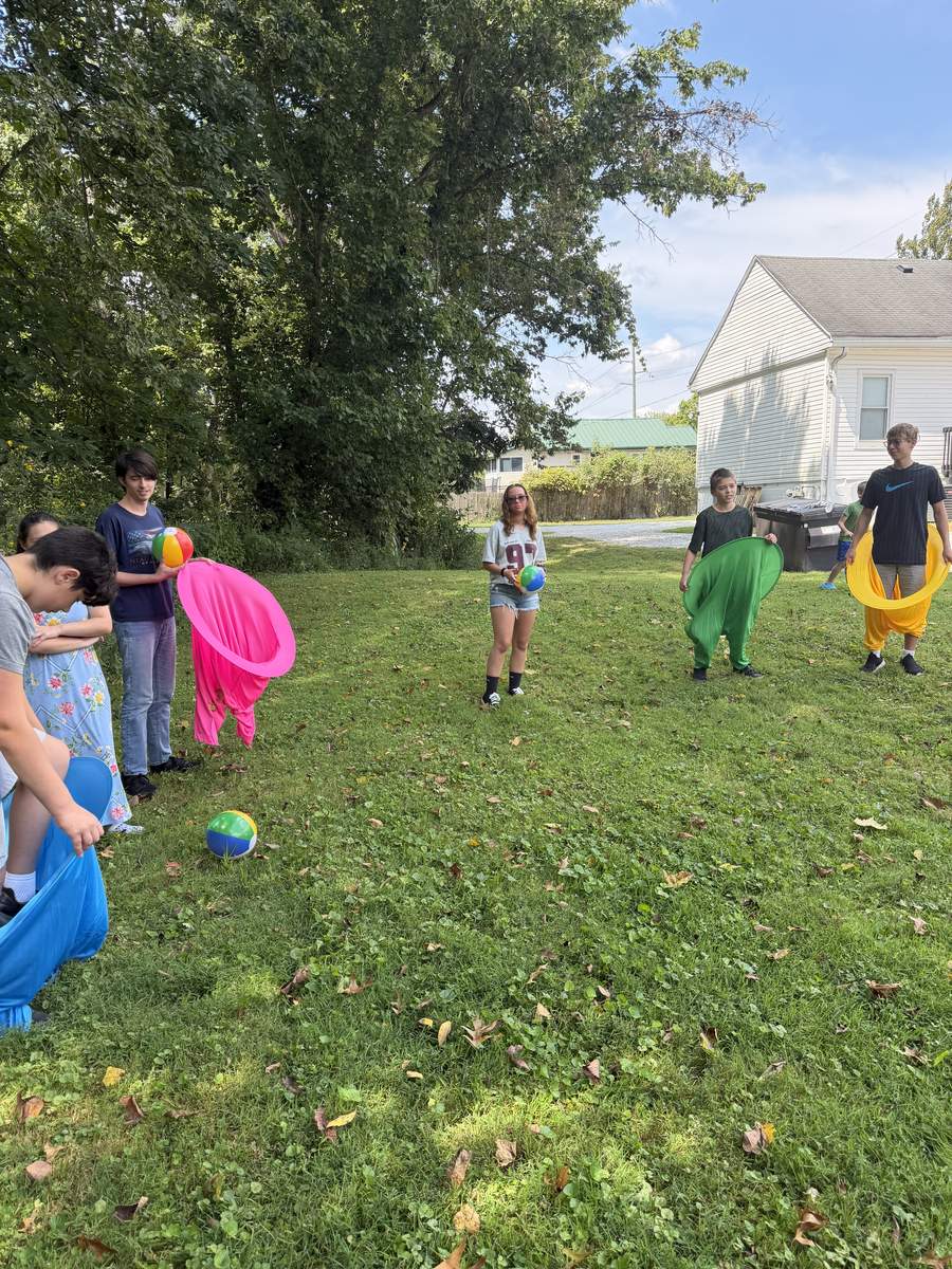 Kids playing an outdoor game with colorful fabric leg costumes outside the church