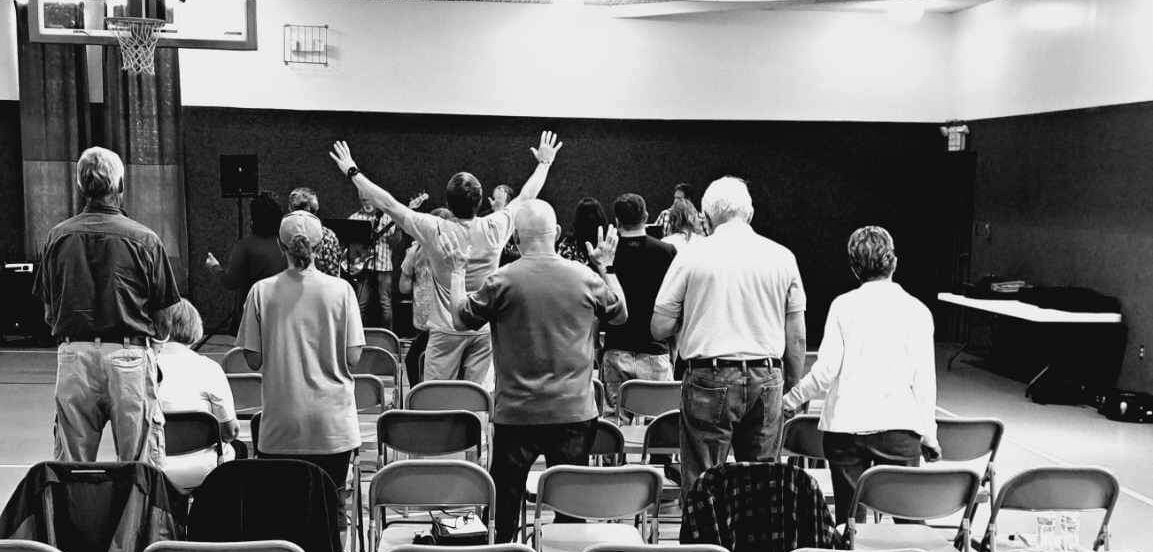 Congregation standing in worship with hands raised